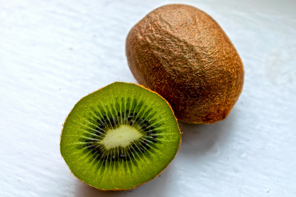 Un kiwi coupé en deux sur une surface blanche