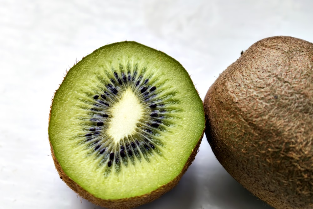 un kiwi coupé en deux sur une surface blanche