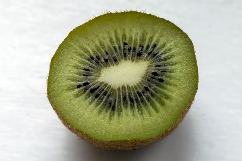 Un kiwi coupé en deux sur une surface blanche