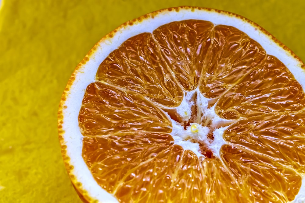 an orange cut in half on a yellow surface