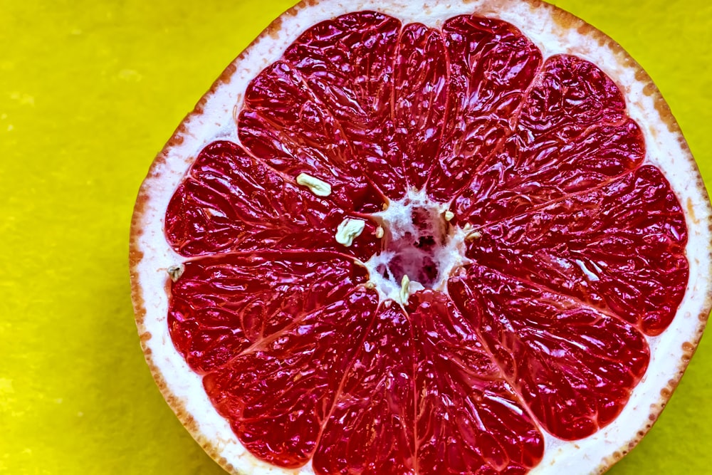 a grapefruit cut in half on a yellow surface