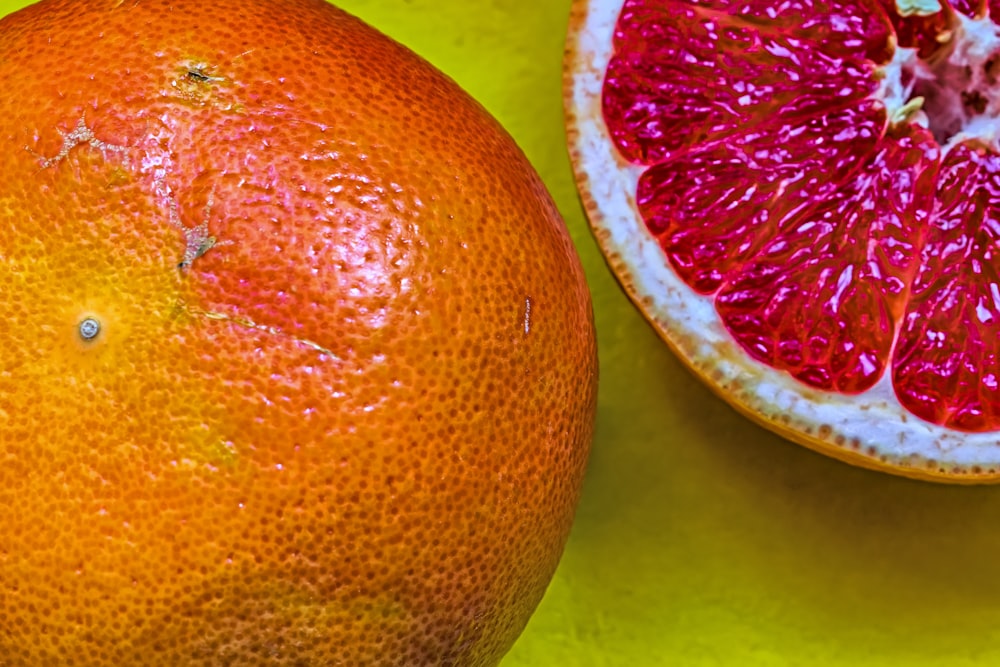 a grapefruit cut in half next to a whole grapefruit