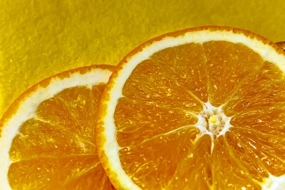 two oranges cut in half on a yellow surface