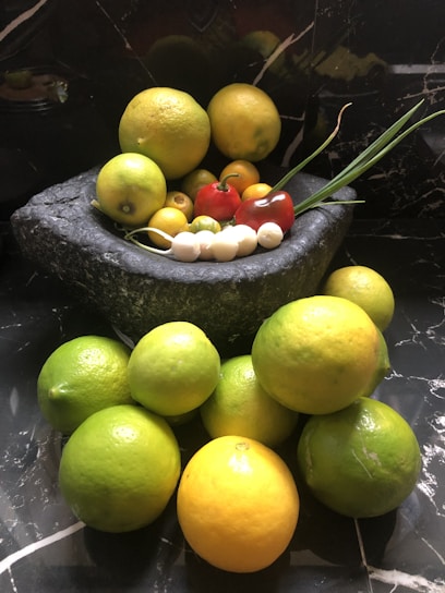 a bowl of lemons and limes on a marble table