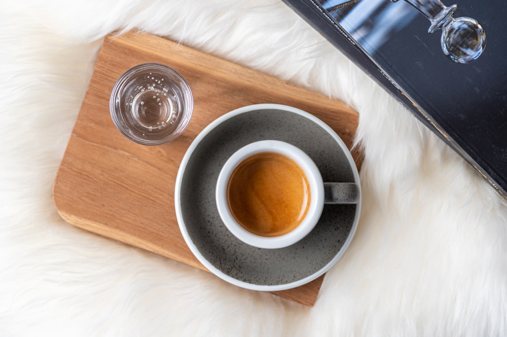 a cup of coffee sitting on top of a wooden tray