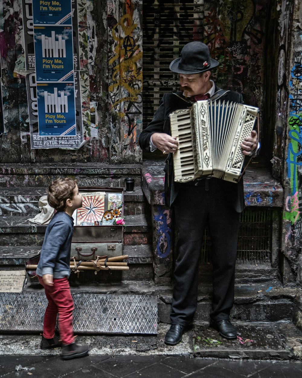 a man playing an accordion next to a little girl