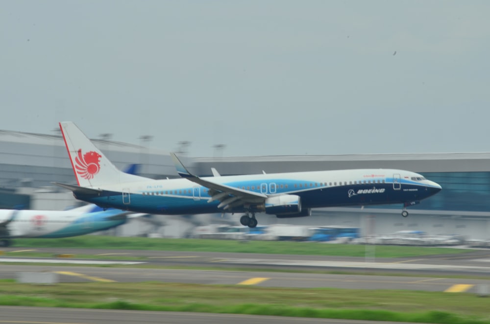 Un avion de ligne bleu et blanc décollant d’une piste d’aéroport