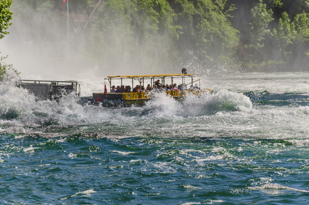 a yellow and black boat with people on it in the water