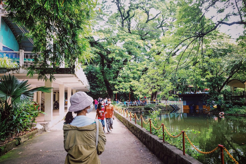 a group of people walking down a path next to a pond