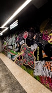A vibrant mural featuring various elements such as a zebra, traffic cones, dice, a stop sign, and colorful text reading 'Rise,' 'Mirpur,' and 'Dhaka.' The artwork incorporates dynamic shapes, patterns, and graffiti-style lettering, creating an urban and energetic scene.
