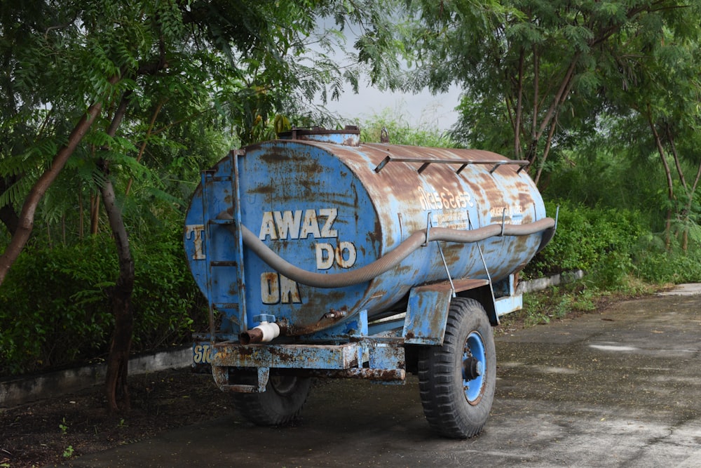 Ein großer blauer Lastwagen, der neben einem üppigen grünen Wald geparkt ist