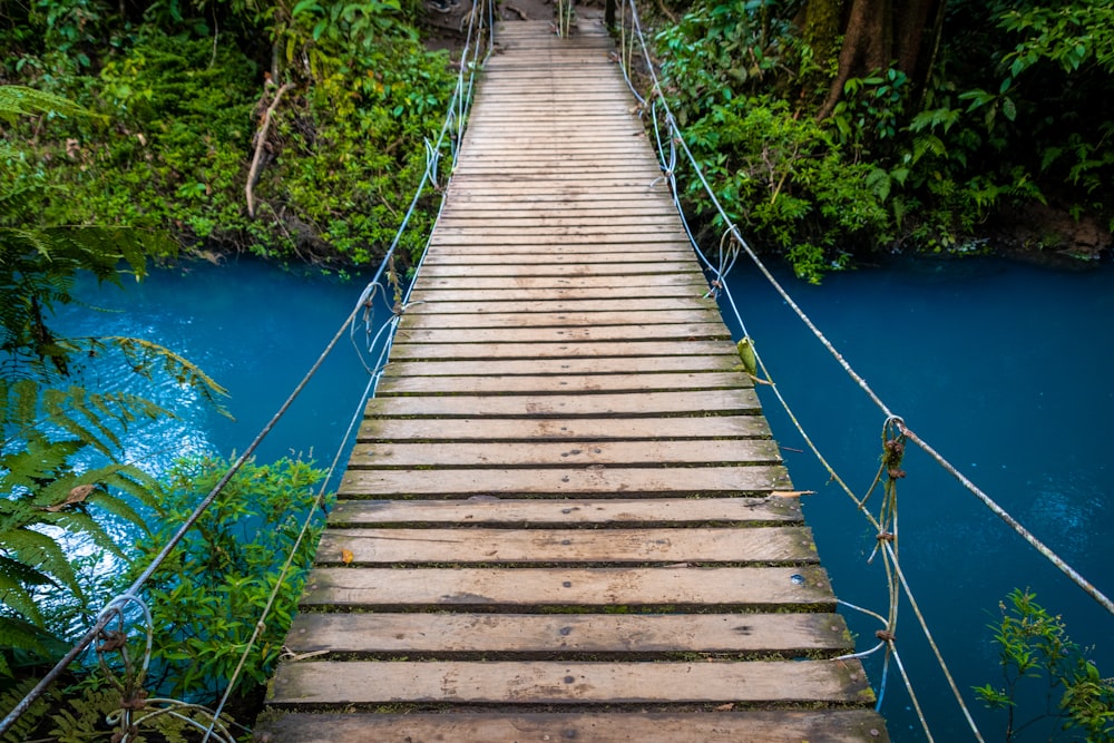 a wooden suspension bridge over a blue river