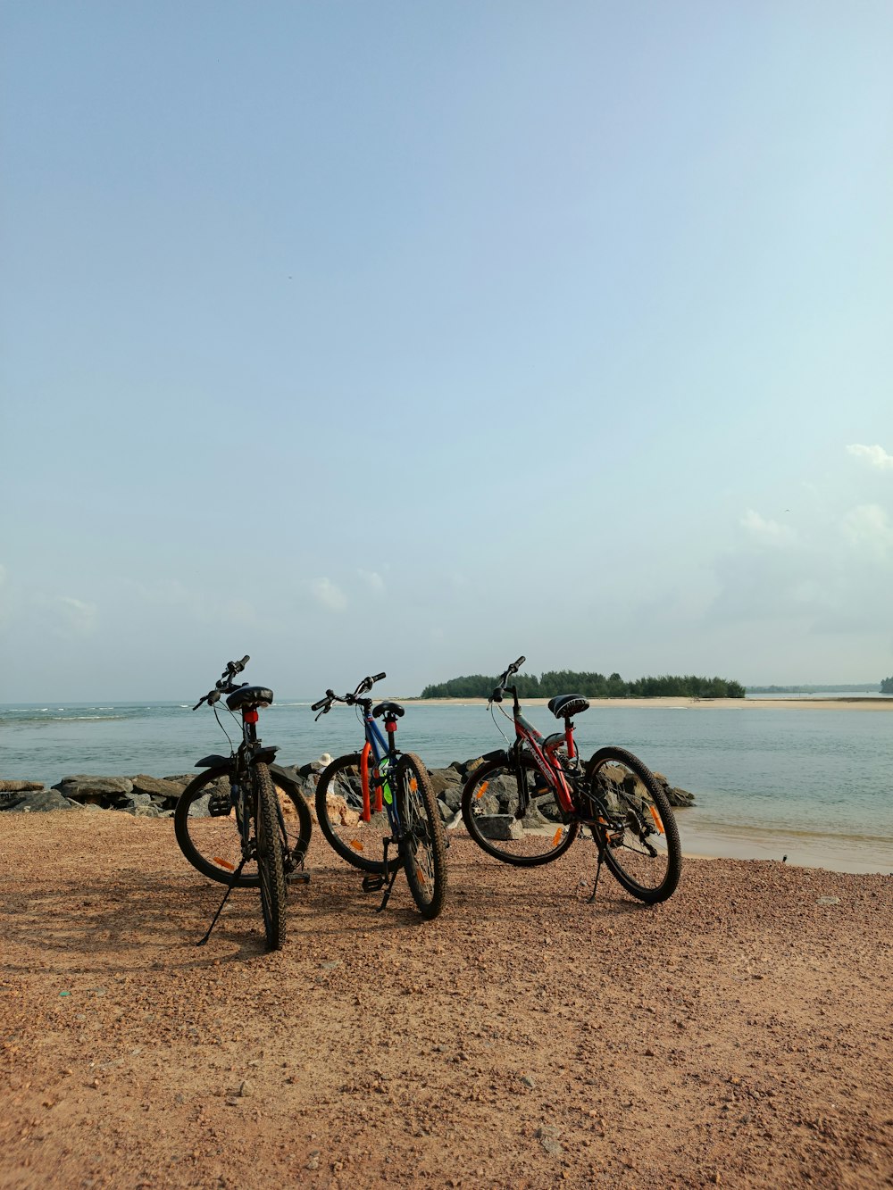 three bikes are parked on the beach by the water