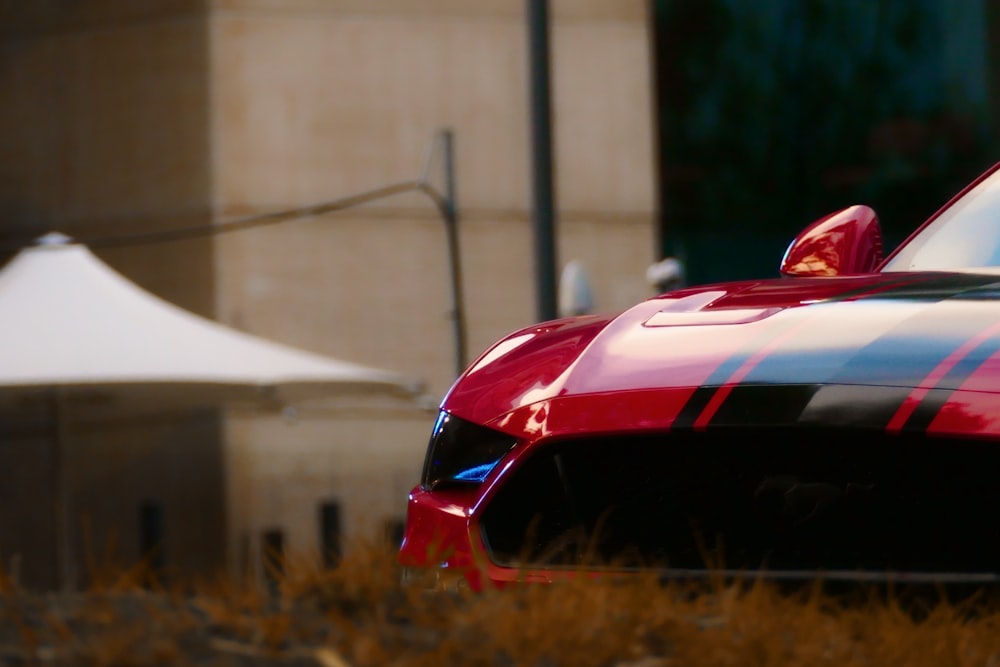 a red and black sports car parked in front of a building