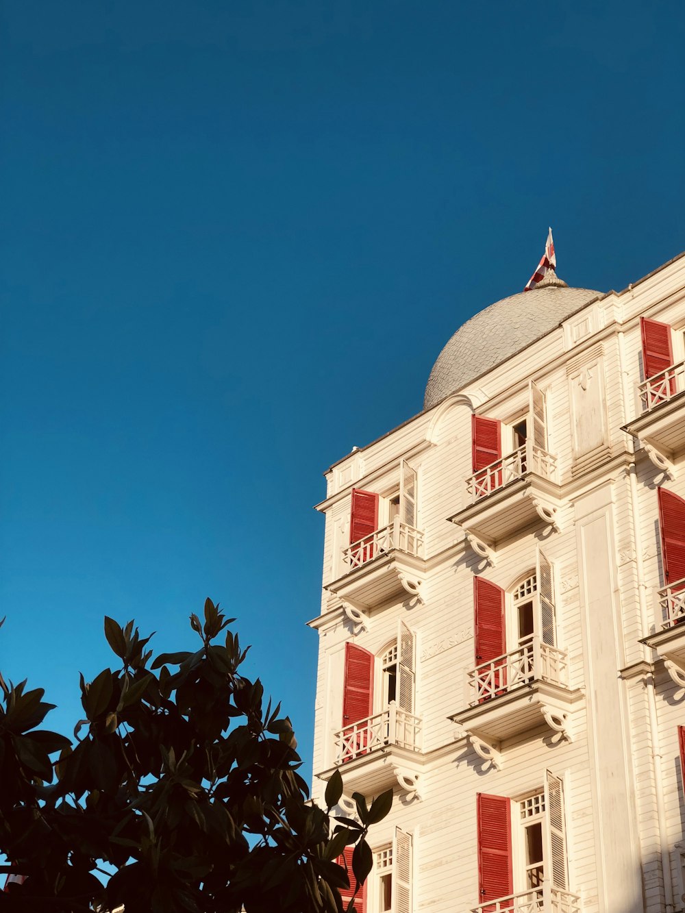 a white building with red shutters and a clock