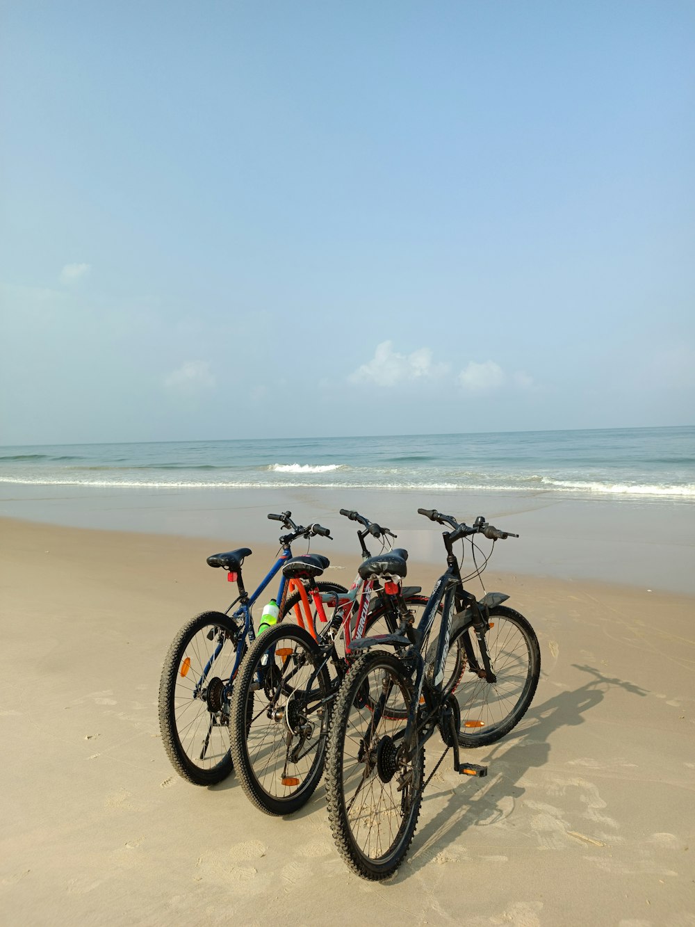 a group of bikes parked on top of a sandy beach