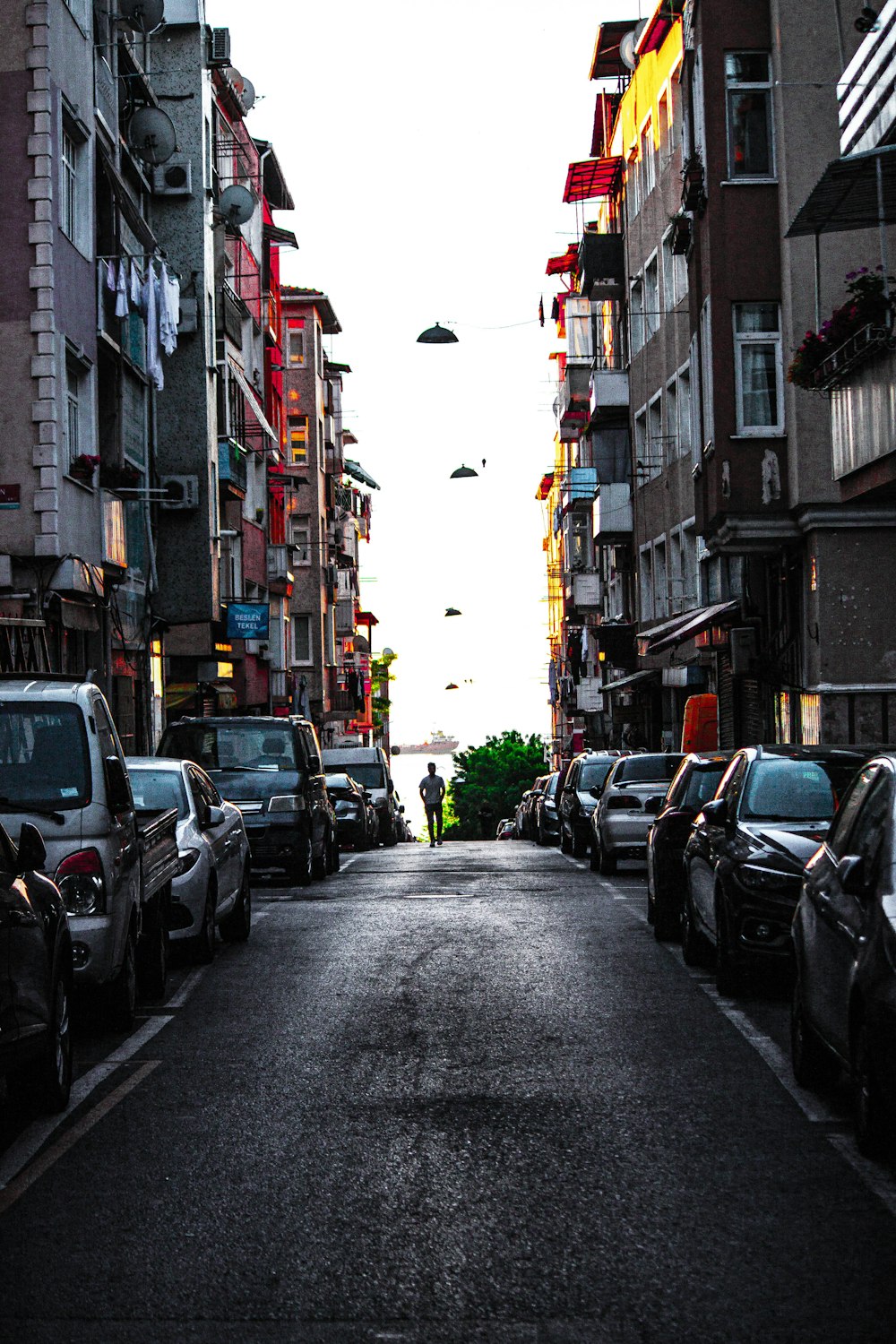 a street lined with parked cars next to tall buildings