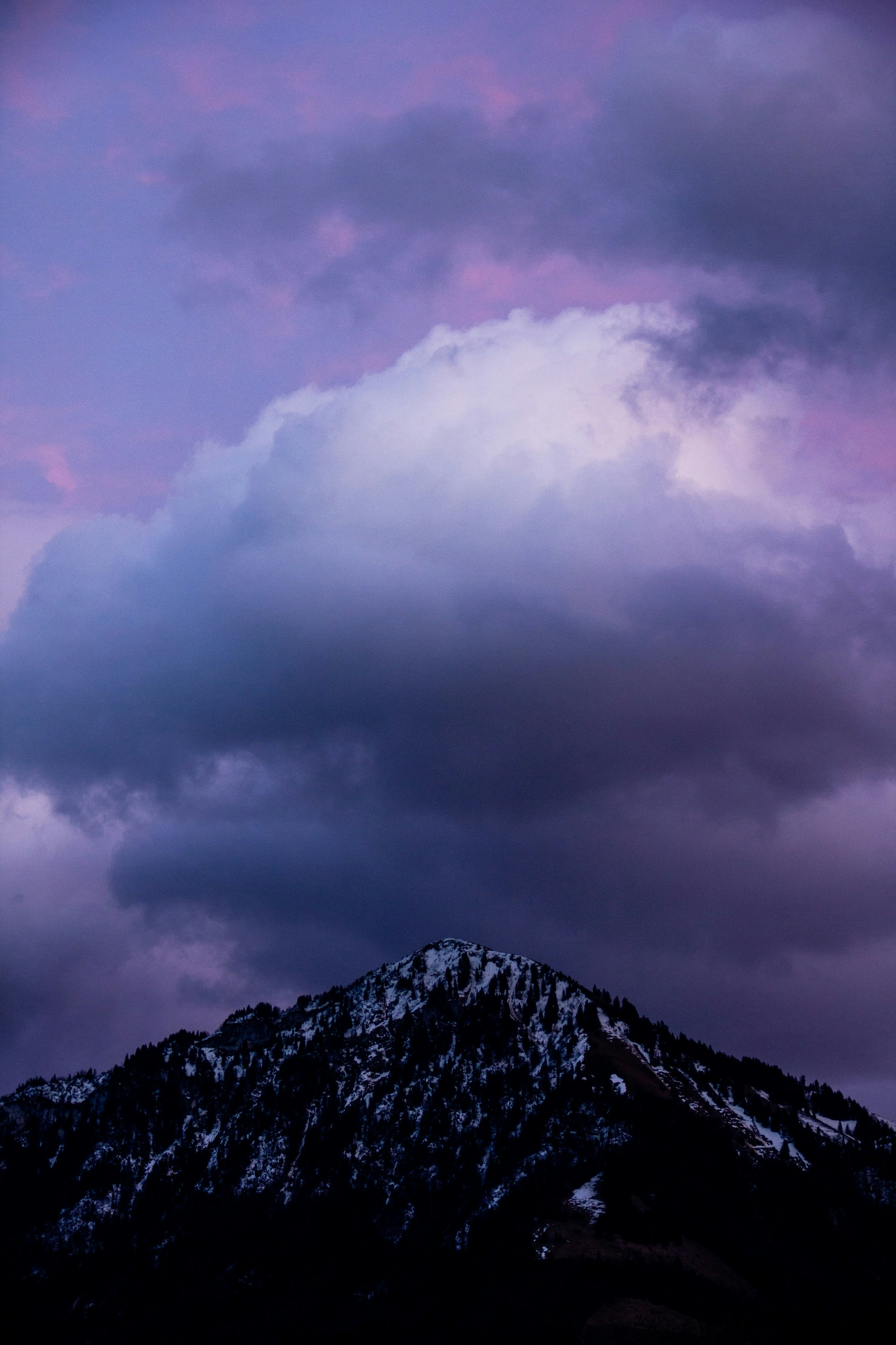 a mountain covered in snow under a cloudy sky