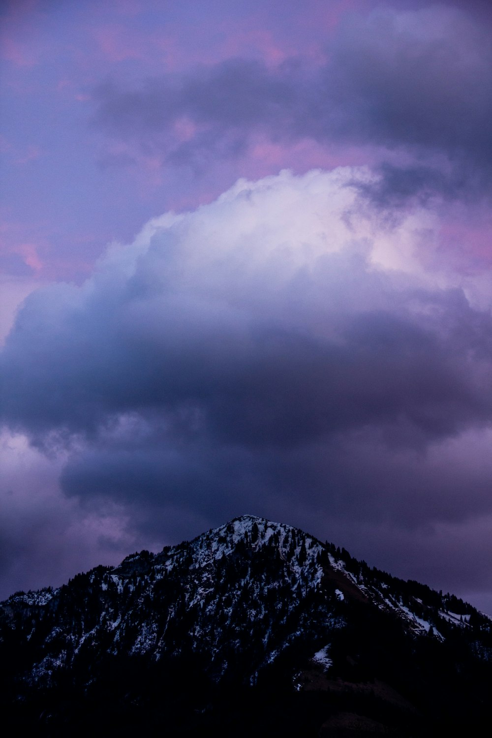 a mountain covered in snow under a cloudy sky