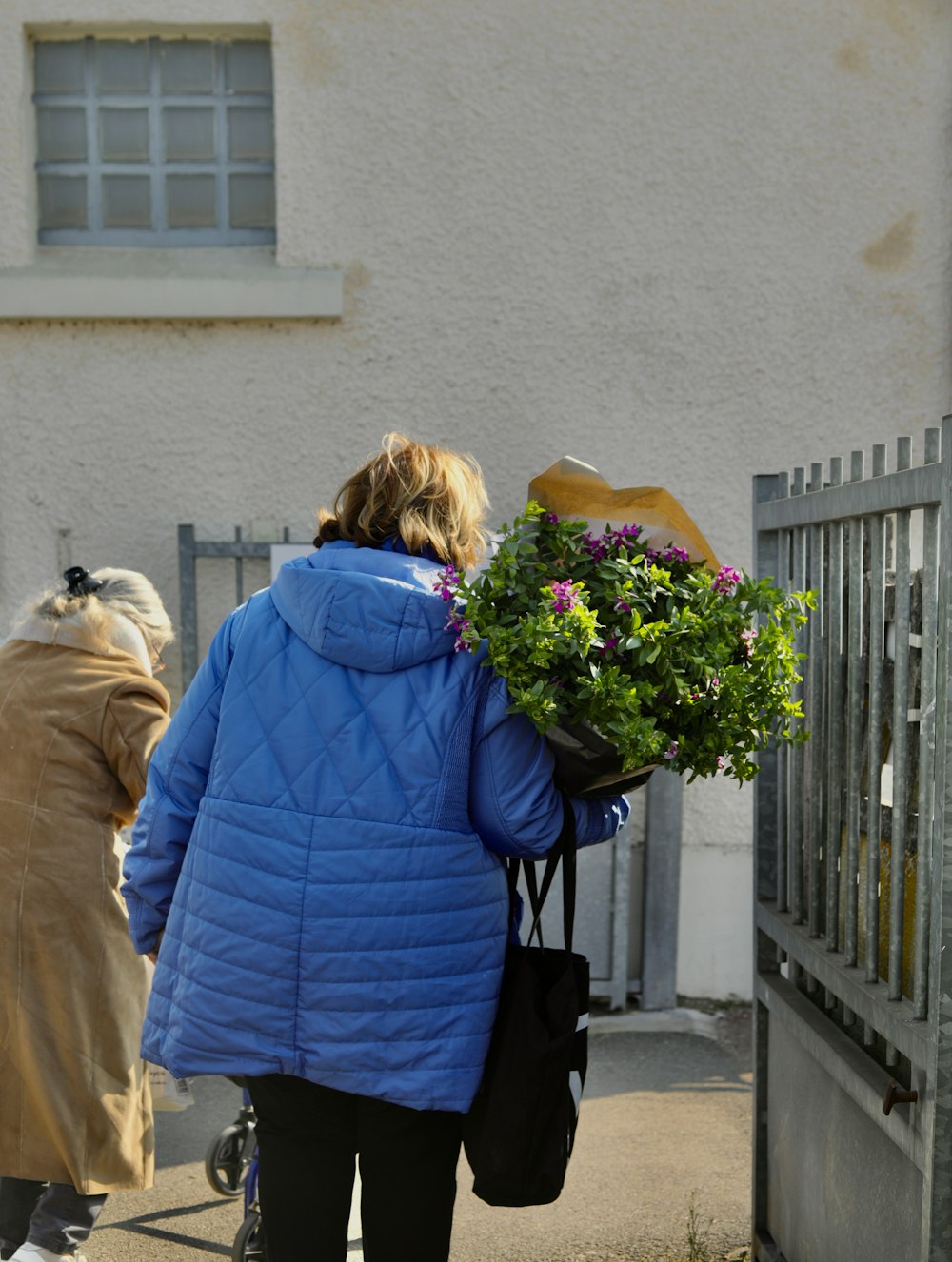 a woman in a blue jacket carrying a bunch of flowers