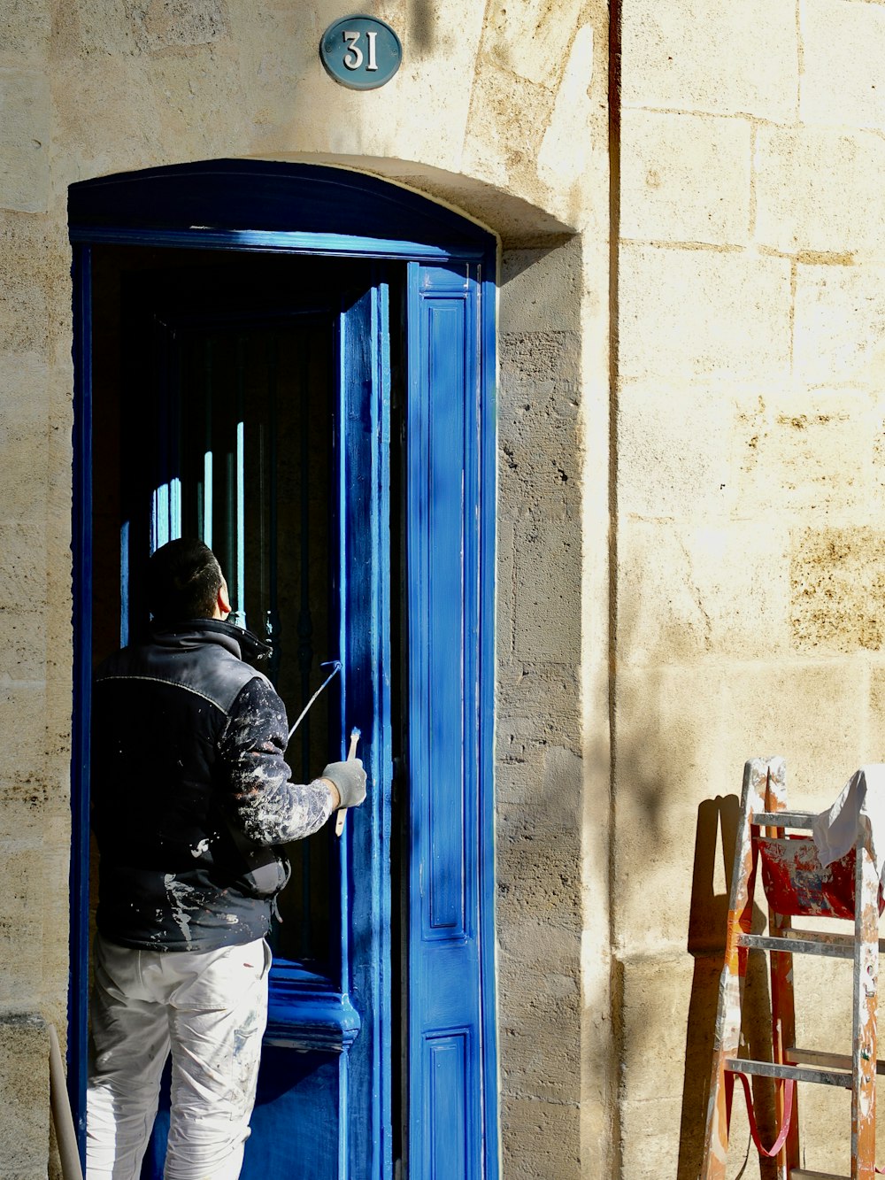 a man in a black jacket is opening a blue door