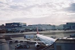 A smiling driver greeting guests at Izmir airport with a backdrop of clear skies.