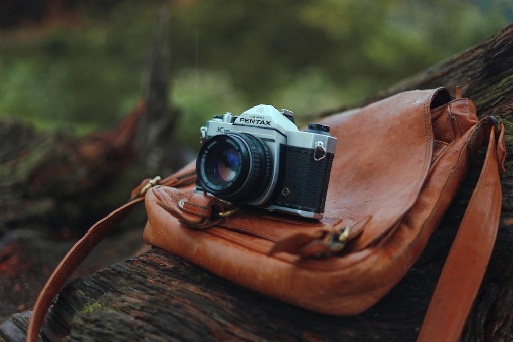 a camera sitting on top of a brown leather bag