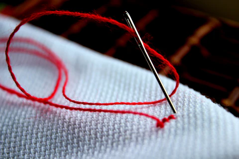Close-up of a needle stitching thread into cloth
