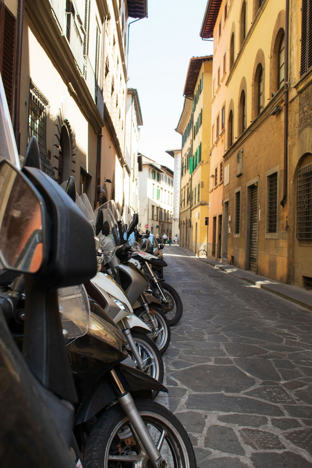 a row of motorcycles parked on the side of a street