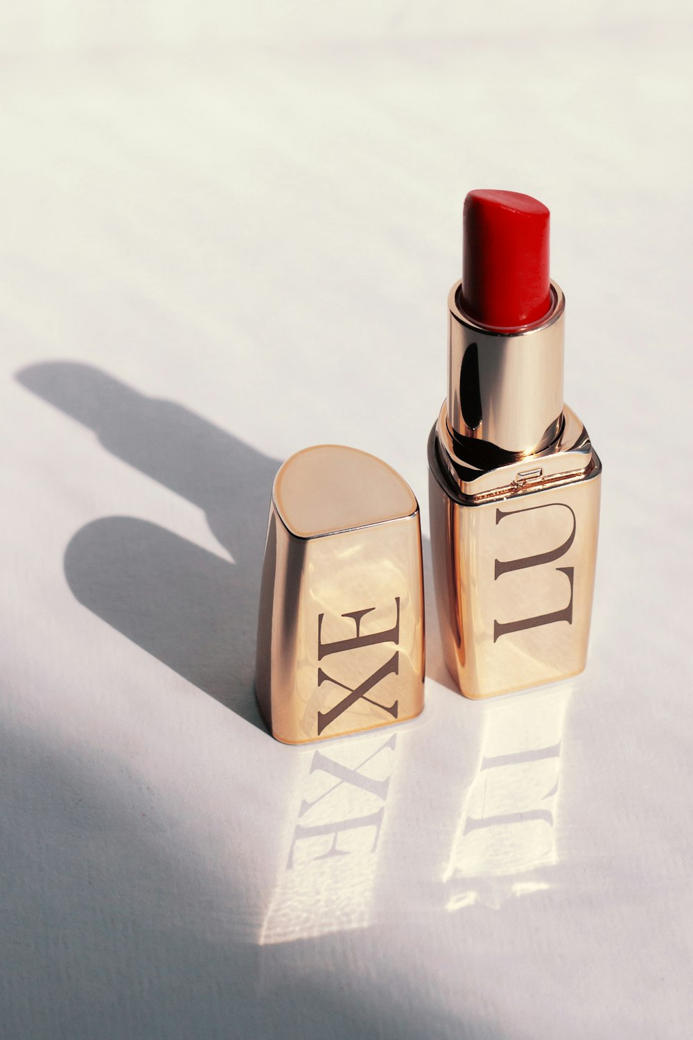 a red lipstick sitting on top of a white surface