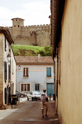 a person walking down a dirt road in front of a brick building