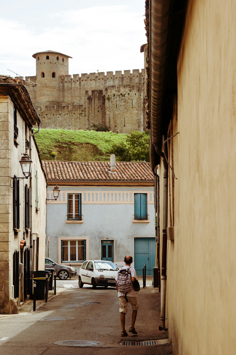 a person walking down a dirt road in front of a brick building