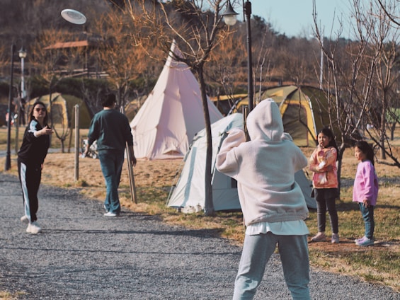 A group of casual disc golfers laughing and throwing discs through a sun-dappled forest clearing.