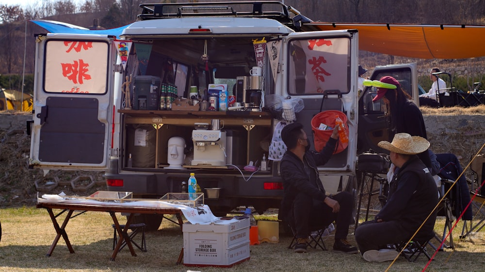 a couple of people sitting in front of a van