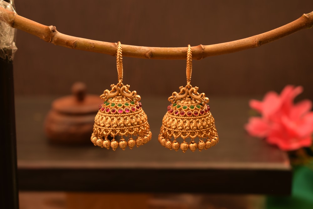 a pair of gold earrings hanging from a twig