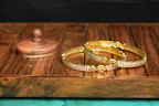 A collection of colorful bangles and matching earrings displayed on a wooden tray.