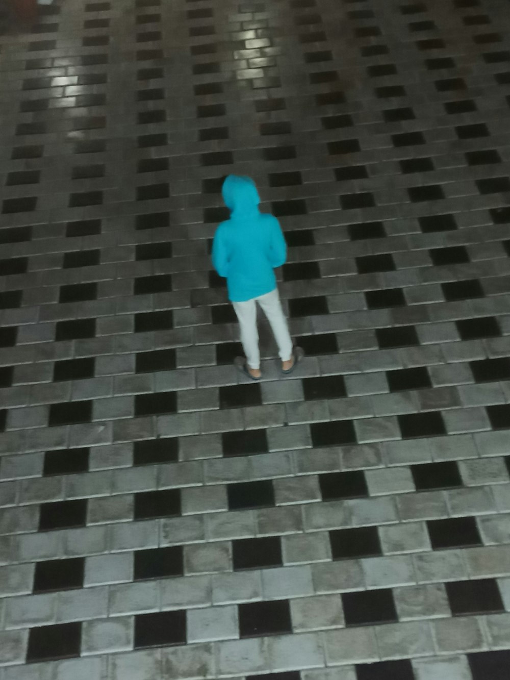 a small child in a blue jacket standing on a tiled floor