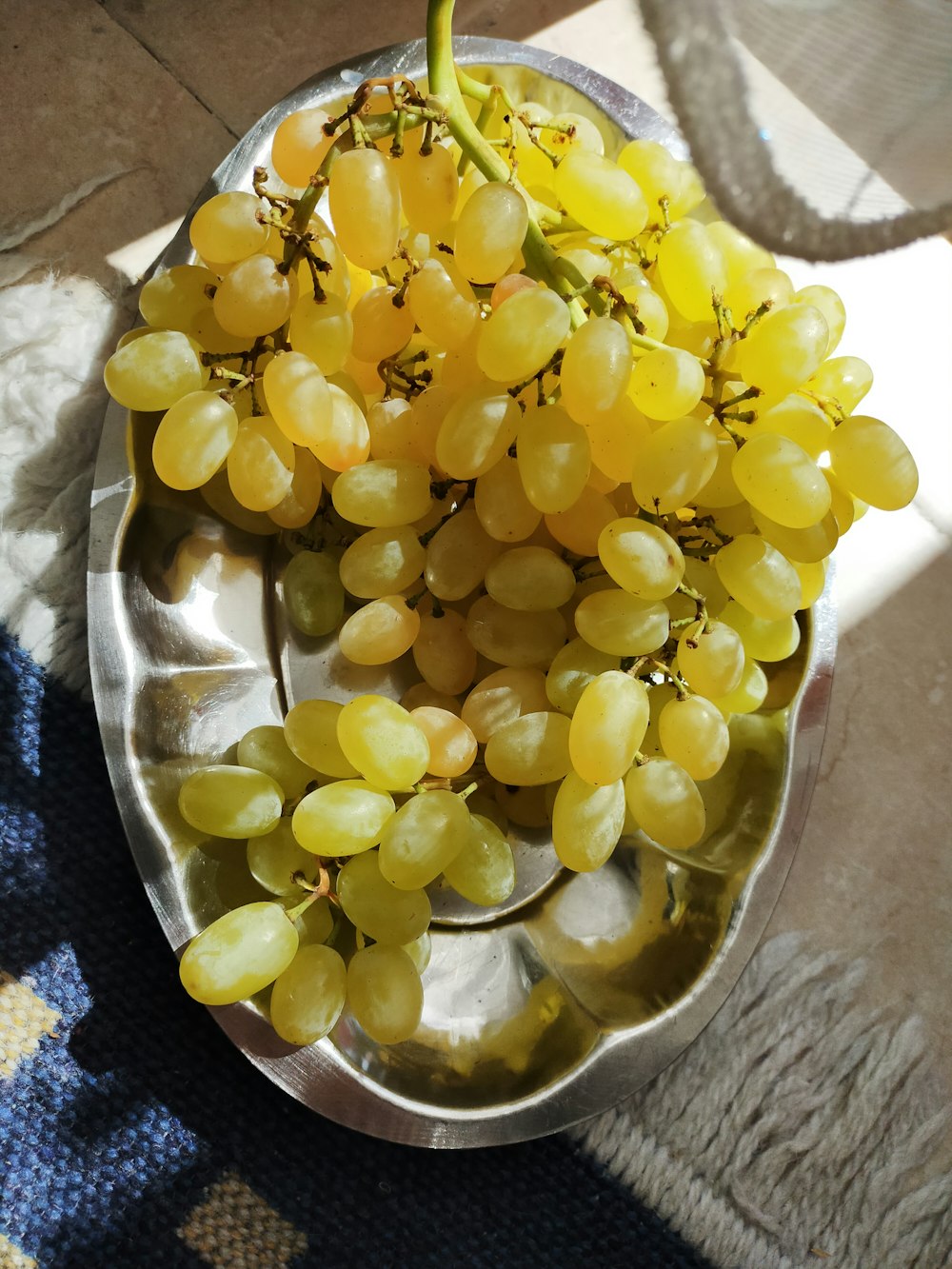 a metal bowl filled with grapes on top of a table