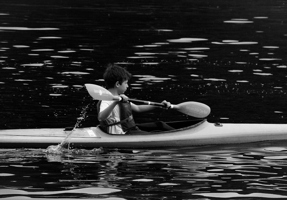 a young boy in a kayak paddling on the water