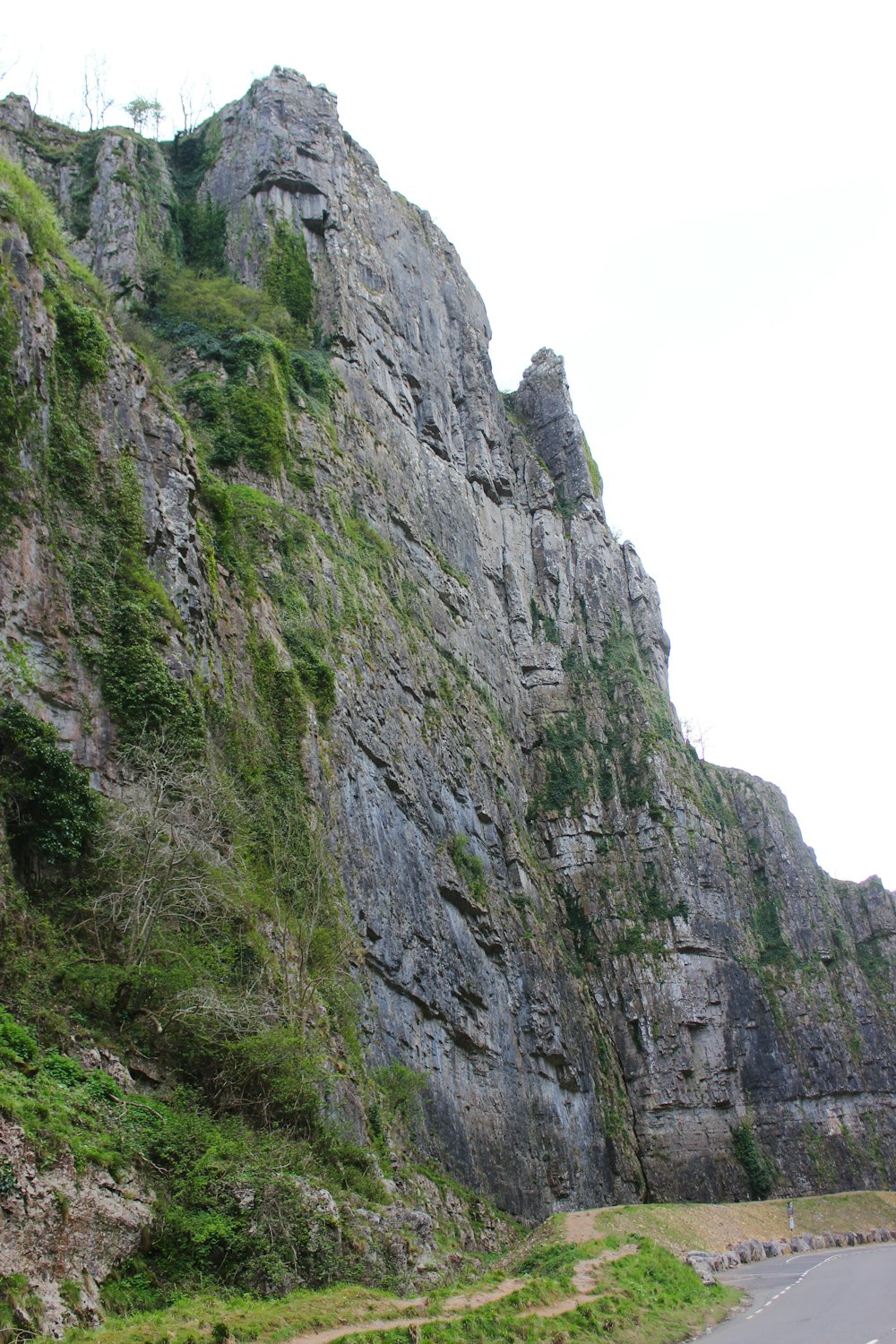 a car driving down a road next to a tall mountain