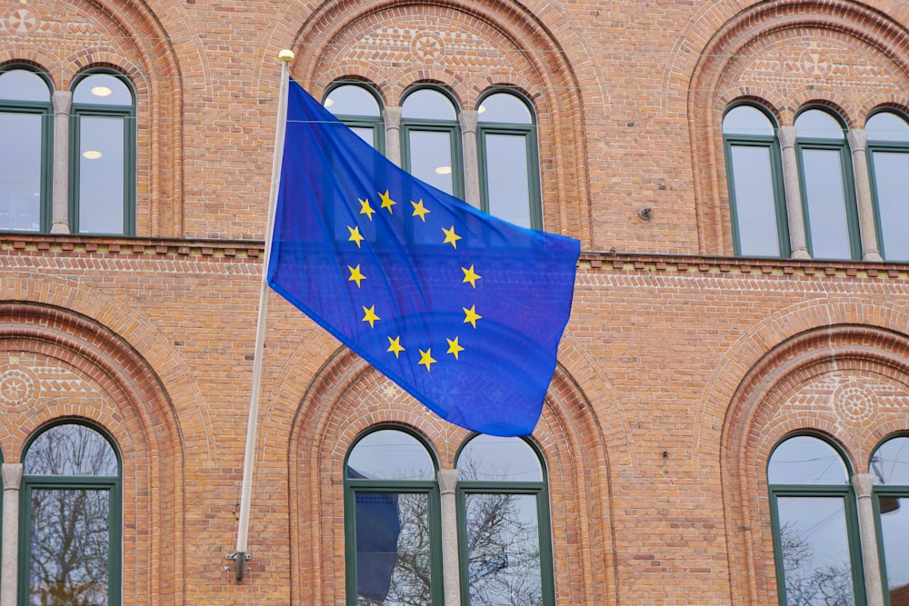 Una bandera europea ondeando frente a un edificio de ladrillo