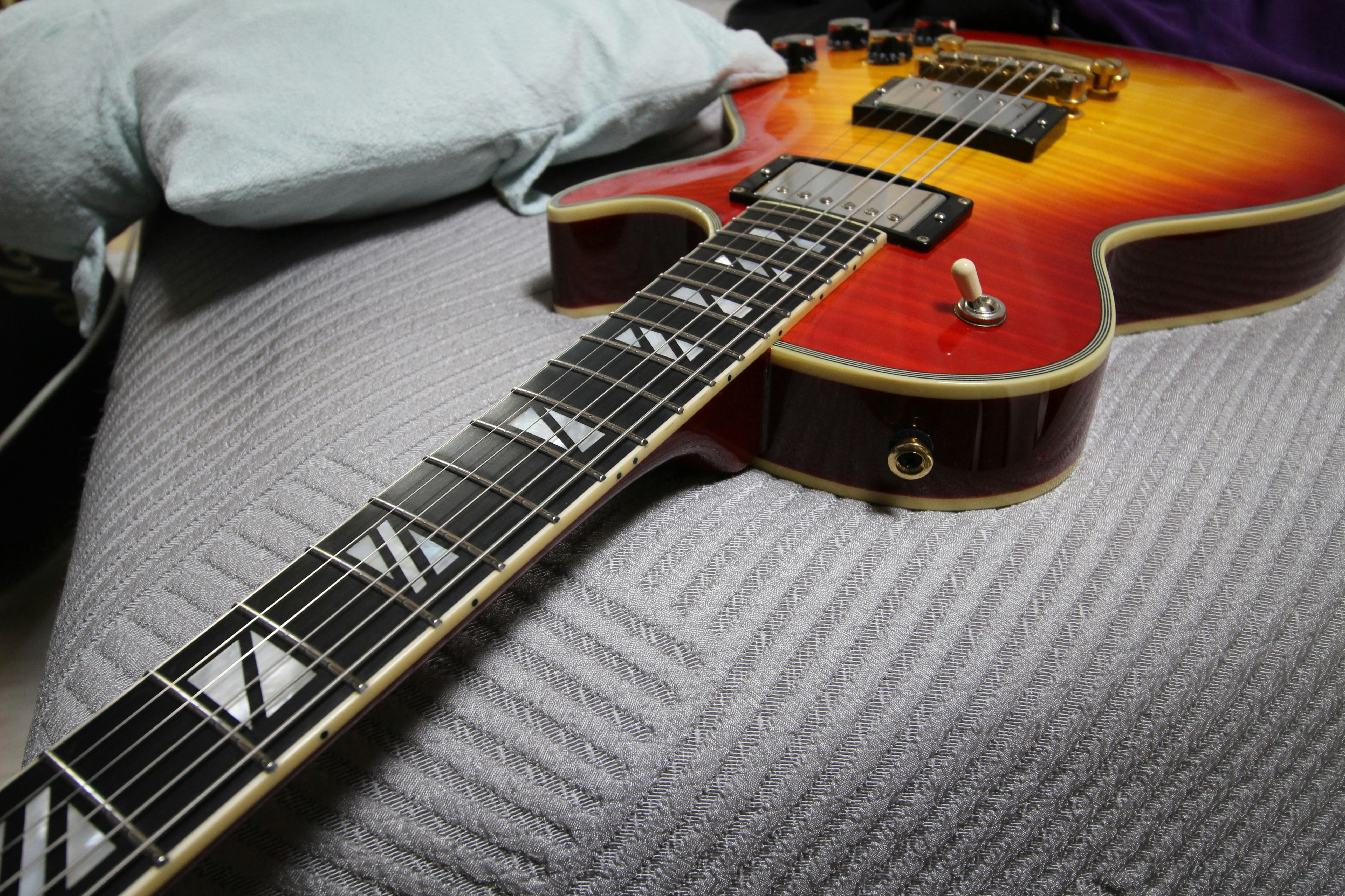 a close up of a guitar laying on a bed