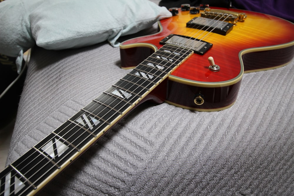 a close up of a guitar laying on a bed
