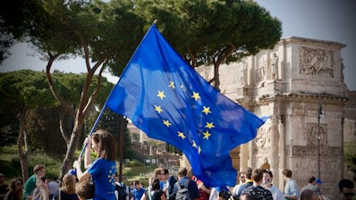 a young girl holding a european flag in front of a crowd of people