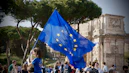 a young girl holding a european flag in front of a crowd of people