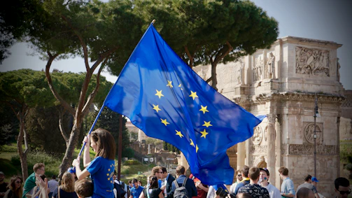 a young girl holding a european flag in front of a crowd of people
