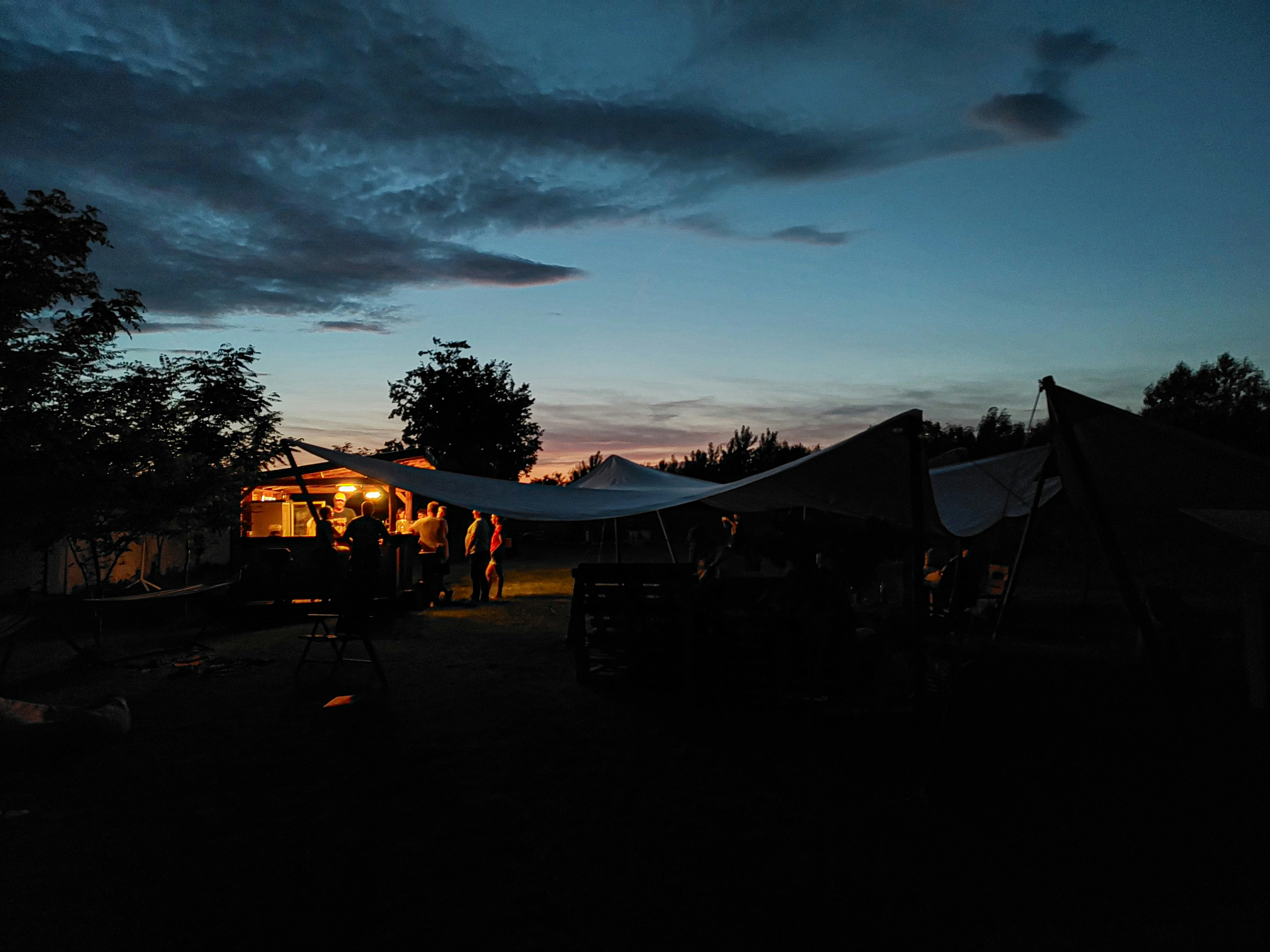 a group of people standing around a tent under a cloudy sky