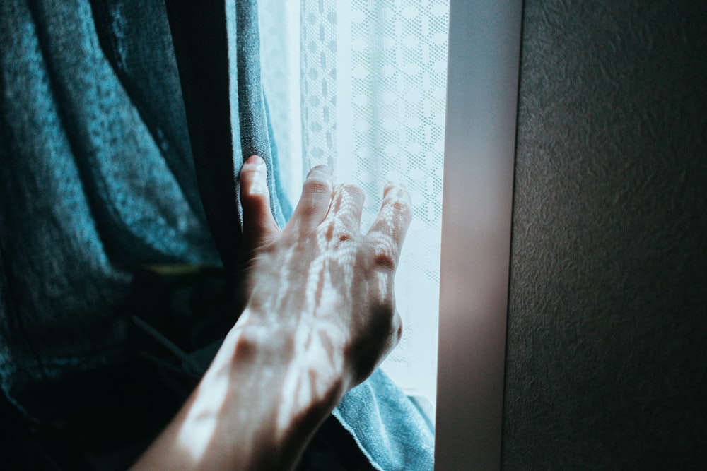 a person's hand reaching out of a window