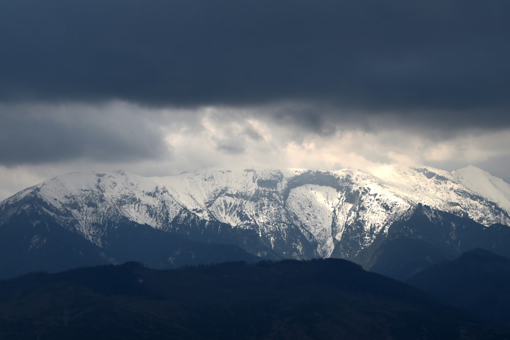 a snow covered mountain range under a cloudy sky