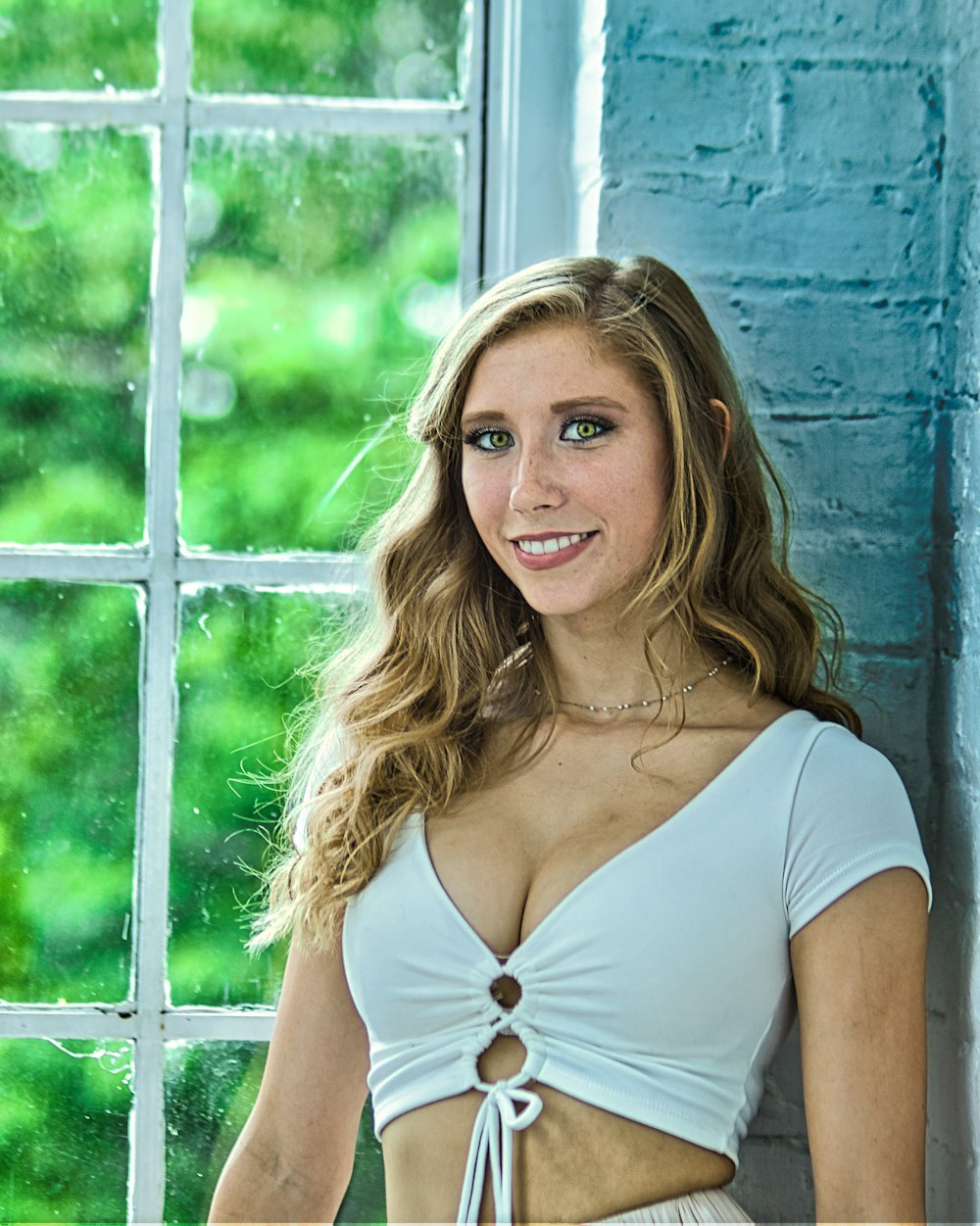 a beautiful young woman standing in front of a window